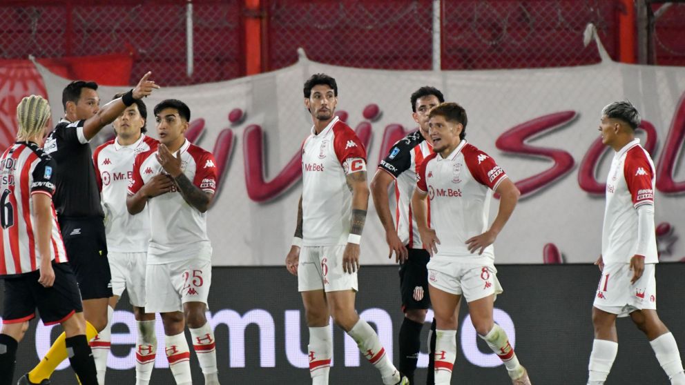 Los jugadores de Huracán le protestan a Tello el claro penal que no fue sancionado por la mano de Damián Martínez.