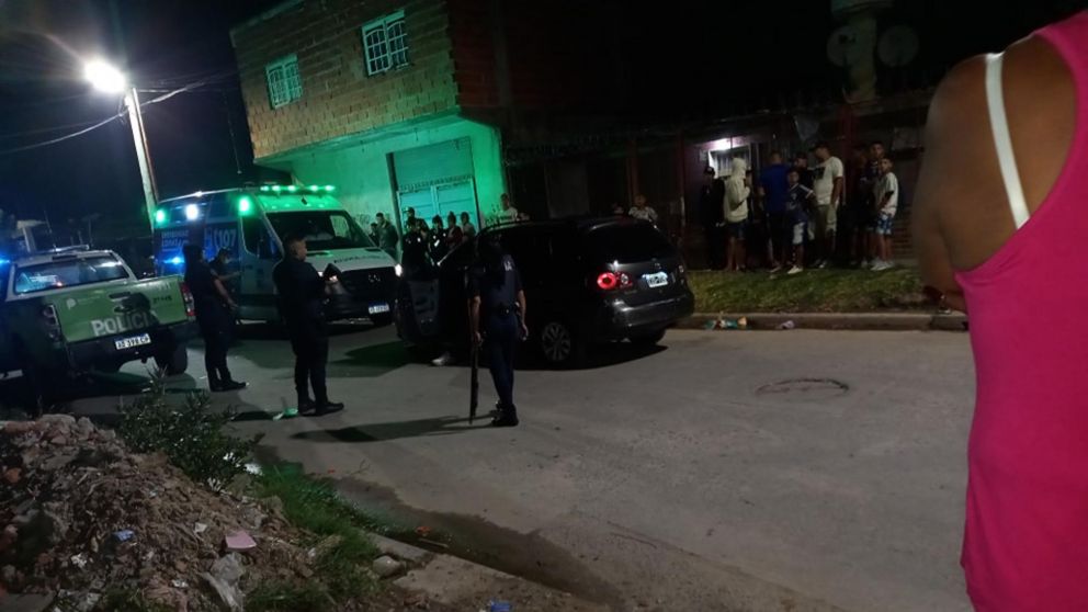 Los policías, rodeados por vecinos, revisan el coche que conducía la víctima.