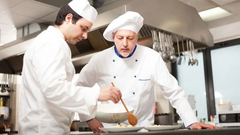 Chief chef watching his assistant garnishing a dish