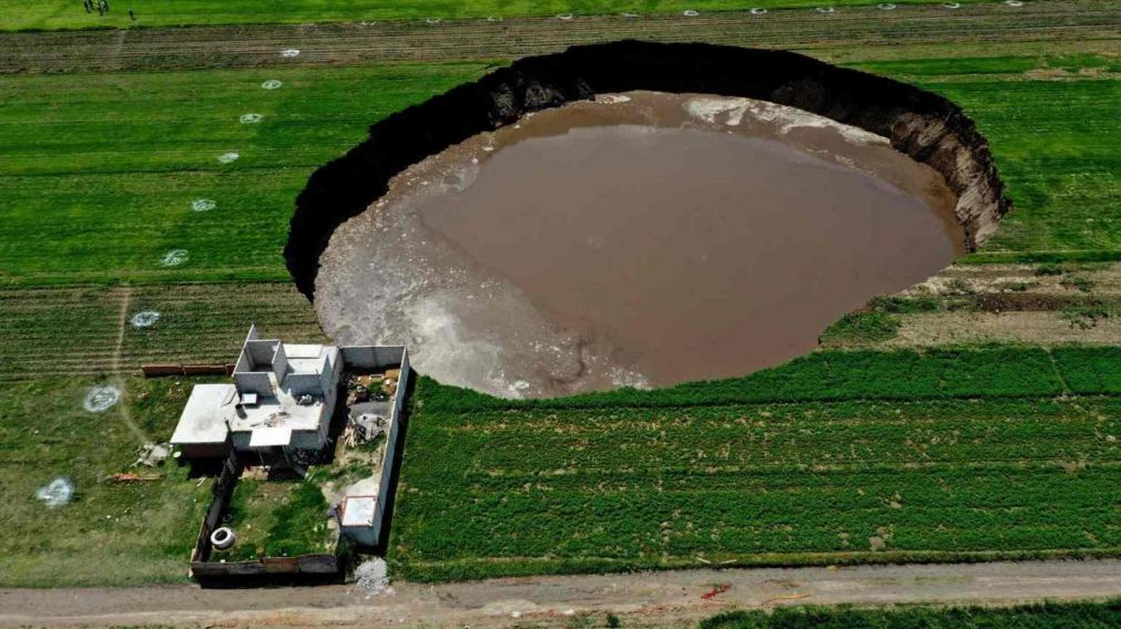 Este impresionante agujero en la tierra está relleno de agua y rodeado de campo. (Gentileza AFP)