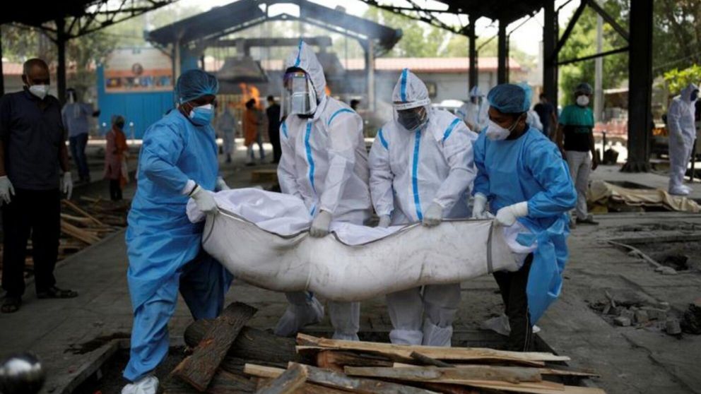 Trabajadores de la salud y familiares llevan el cuerpo de un hombre para que sea cremado (Reuters).