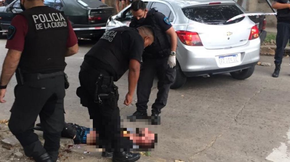 El delincuente baleado yace en el pavimento, rodeado por los efectivos policiales.