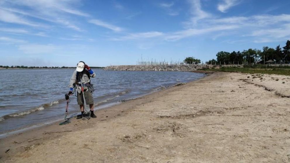 Alberto Chiaramonte con su buscador de metales en la costa de Rosario.