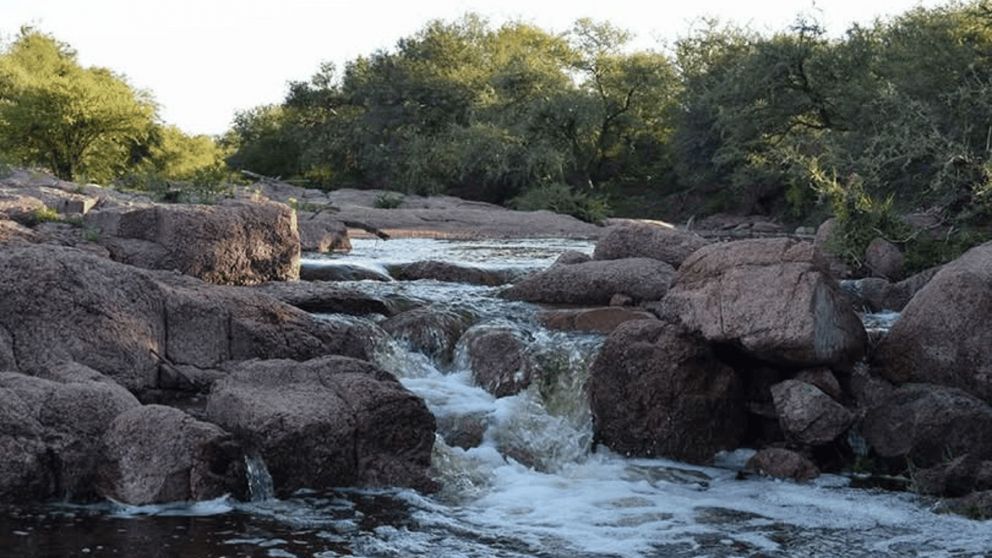 El arroyo descendiendo entre rocas y vegetación, creando un paisaje que invita al descanso.