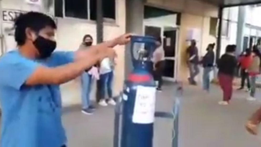 En Orán, Salta, un hombre sanitiza un tubo de oxígeno en la puerta de un hospital.