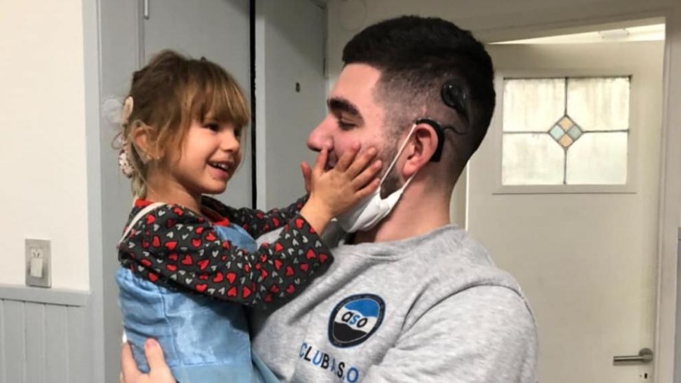 Cala, de cinco años, junto con el joven que le entregó el implante para que pueda oír.