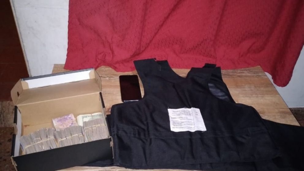 Parte del dinero secuestrado en poder de los detenidos y el chaleco antibalas que fue incautado.