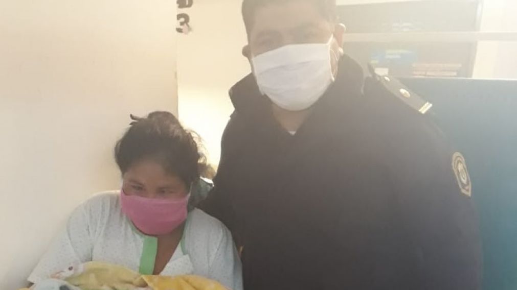 La mujer, de 23 años, junto al nenito y a uno de los policías que la ayudaron a dar a luz.
