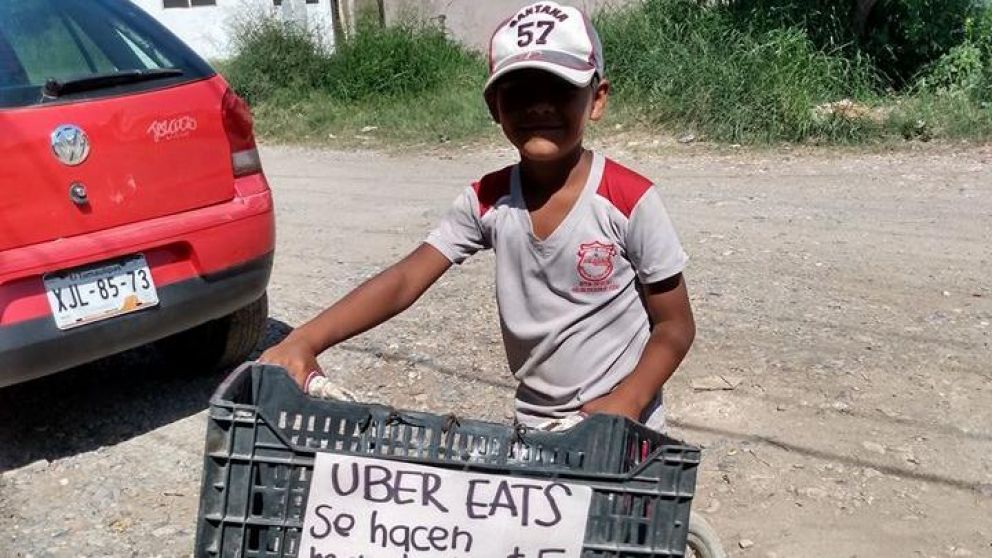 El chico colgó un cartel al frente de su bicicleta ofreciendo los envíos.