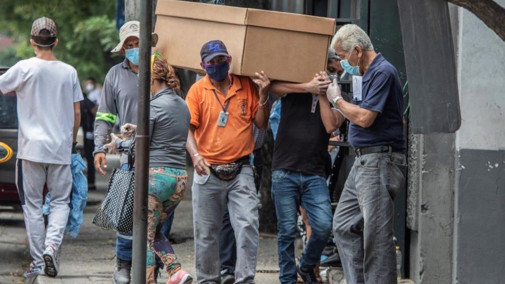 Los trabajadores públicos trasladan ataúdes de cartón.