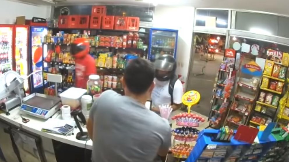 Los delincuentes, con casco puesto, amenazan al empleado.