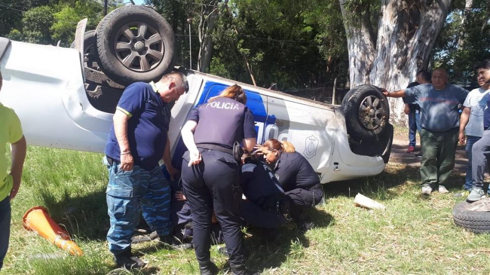 Policías auxilian a sus compañeros dentro del patrullero volcado.