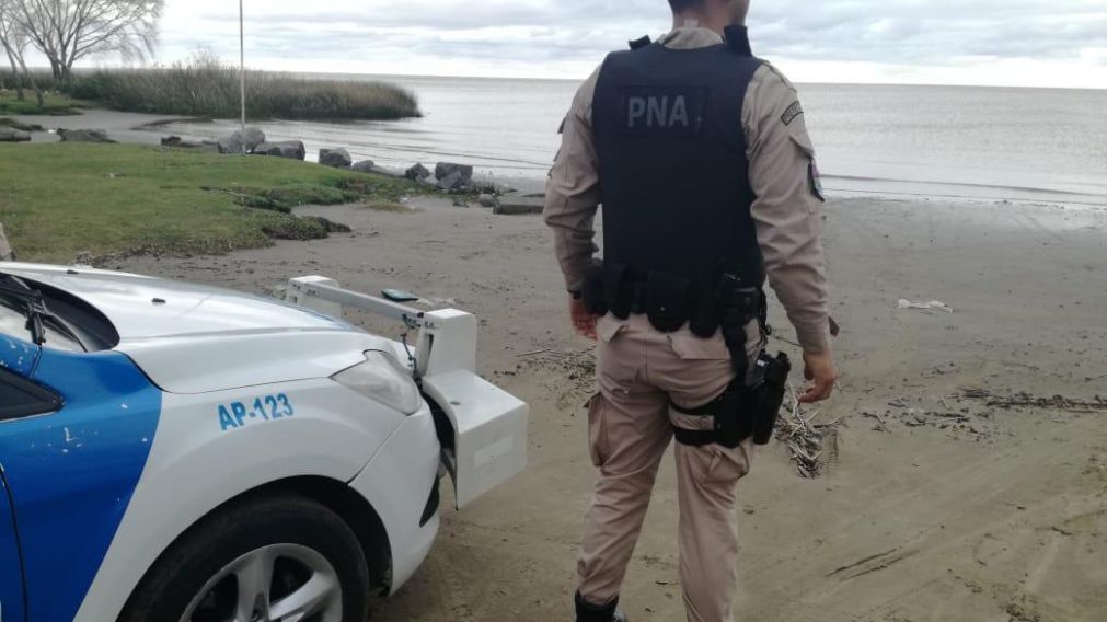 Un agente de Prefectura a orillas del río donde fue hallado el cuerpo.( Prensa Prefectura)