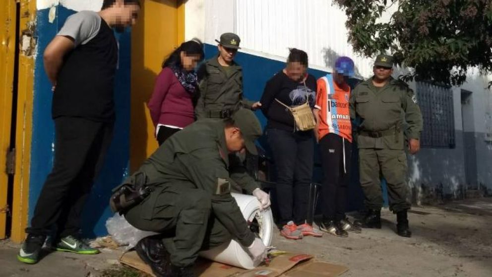 La pareja viendo como un gendarme saca la droga en el termotanque.