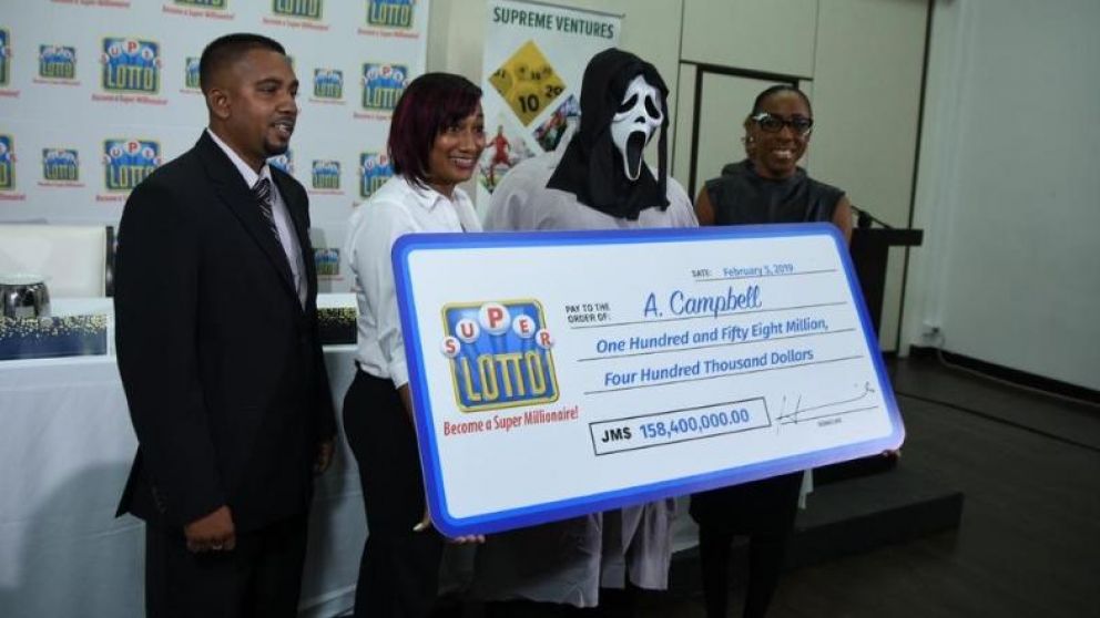 El flamante millonario recibe su cheque ante las autoridades de la lotería.