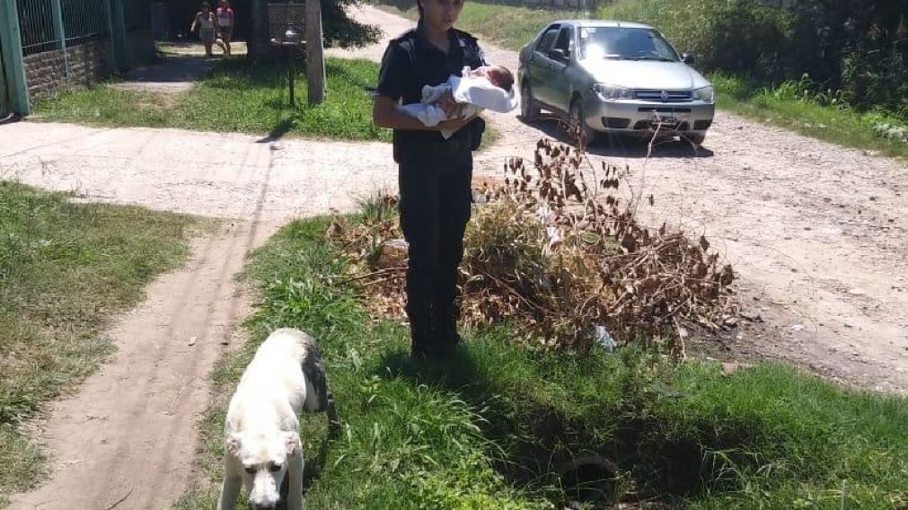 Una mujer policía sostiene en brazos al inocente bebé que fue arrojado entre las bolsas de basura.