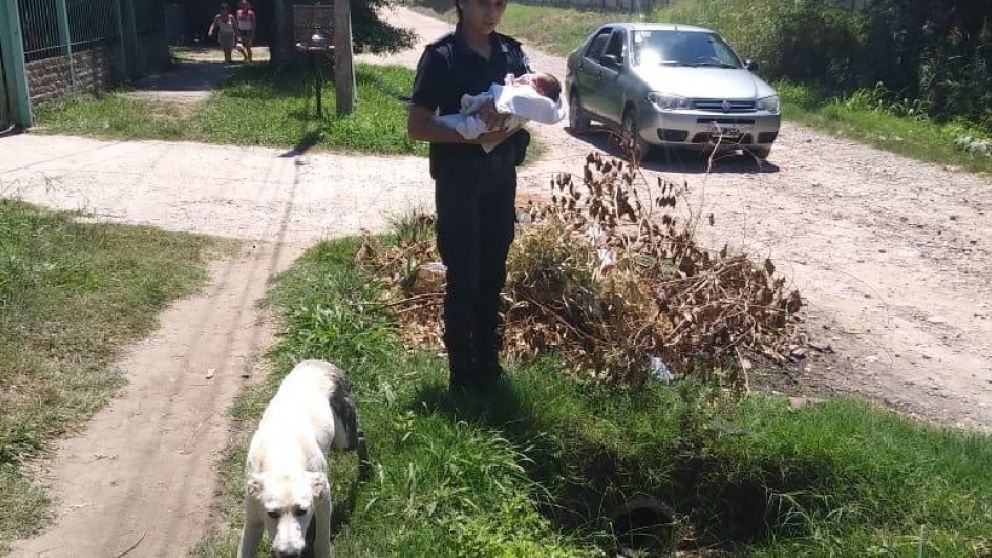 Una mujer policía sostiene en brazos al inocente bebé que fue arrojado entre las bolsas de basura.