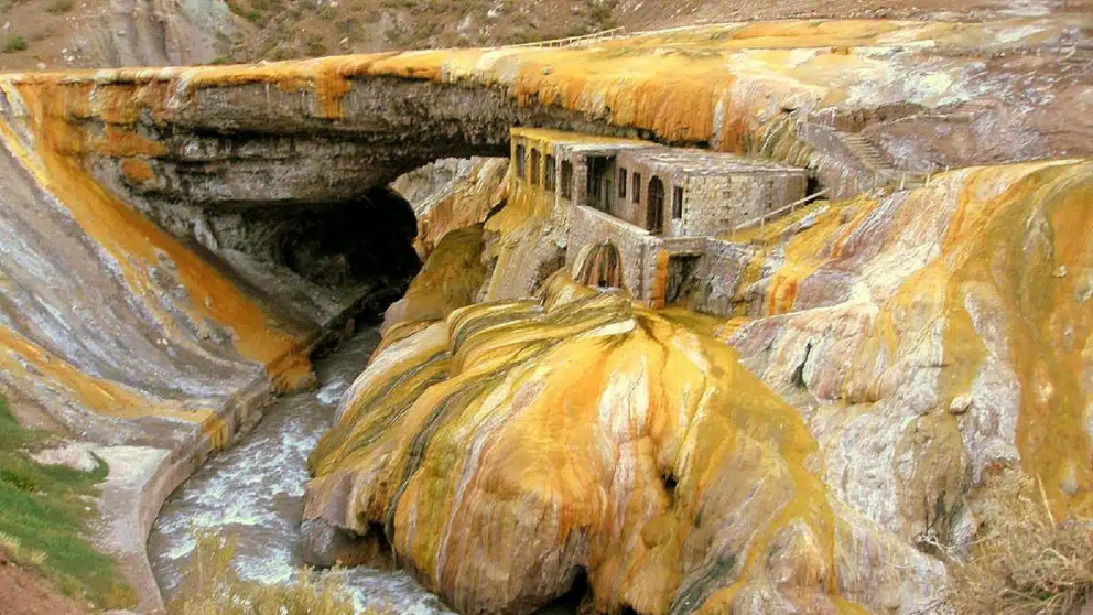 Una formación natural única en la Cordillera de los Andes, rodeada de montañas y colores intensos.