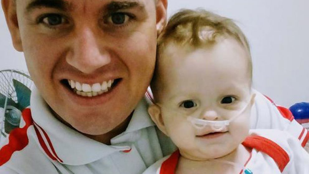 Aaron que es electrodependientes, en brazos de su papá.