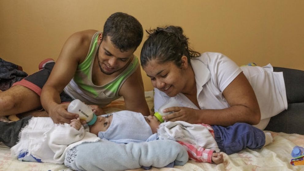 Los padres alimentan con mamaderas a los bebés unidos por la cabeza.