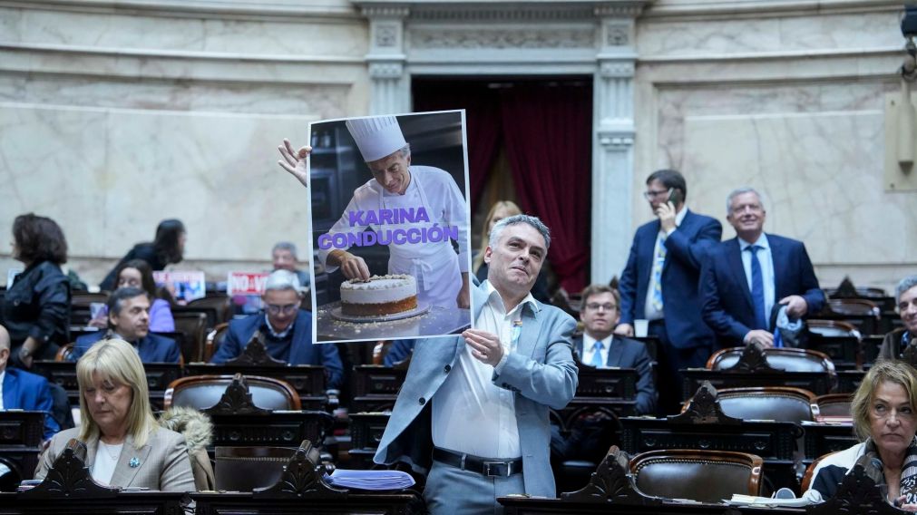 El diputado Esteban Paulón sostiene el cartel sobre Mauricio Macri y Karina Milei.