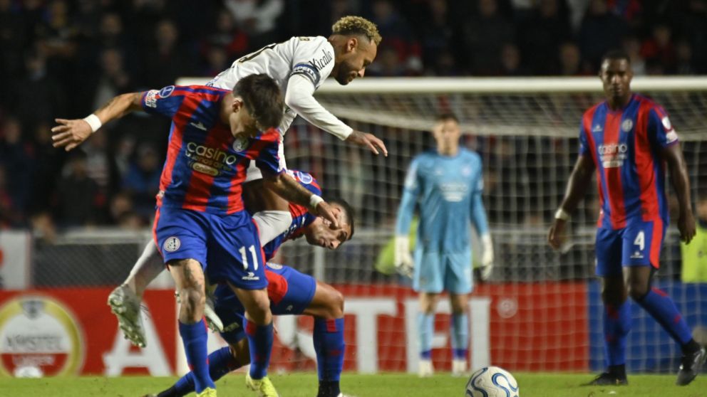 Neymar intenta pasar entre dos jugadores de San Lorenzo y le cometen infracción.