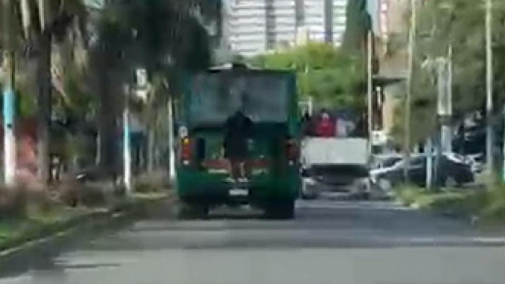 Imprudencia al límite: filman a un joven colgado de un 85 en plena mañana